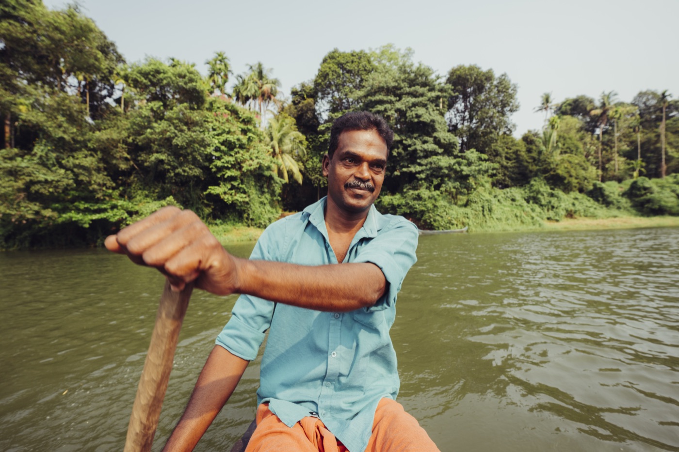 A boatman poling his canoe across the river